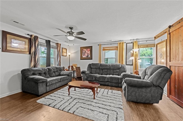 living area with a textured ceiling, a healthy amount of sunlight, wood finished floors, and visible vents