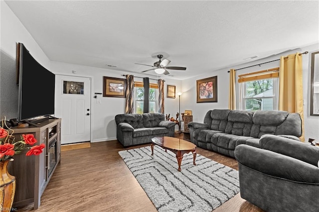 living room featuring wood finished floors, baseboards, a ceiling fan, and visible vents