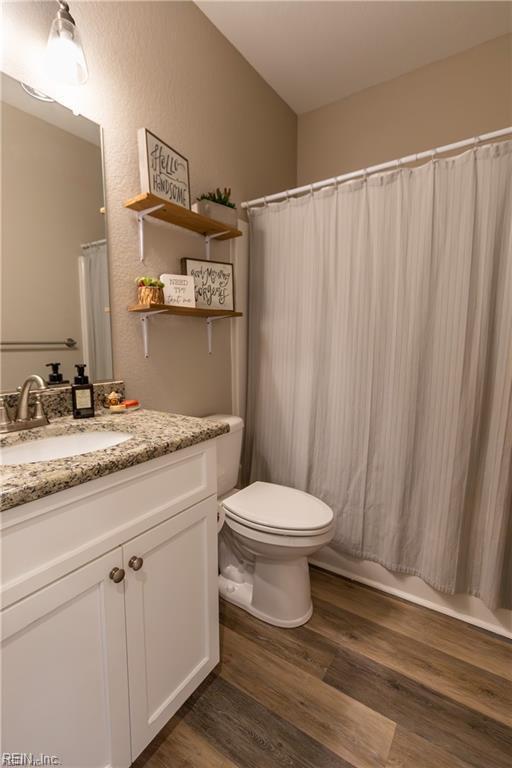 full bathroom featuring wood finished floors, toilet, and vanity