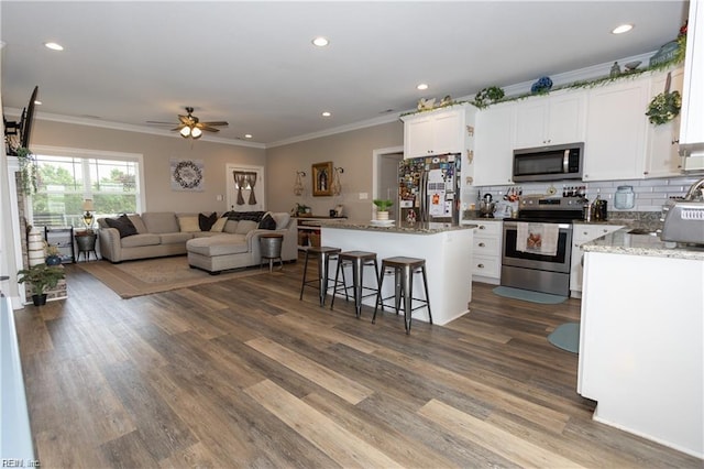 kitchen with a kitchen island, tasteful backsplash, open floor plan, stainless steel appliances, and ceiling fan