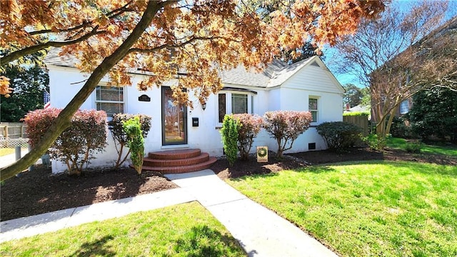 view of front of home with stucco siding, fence, and a front yard