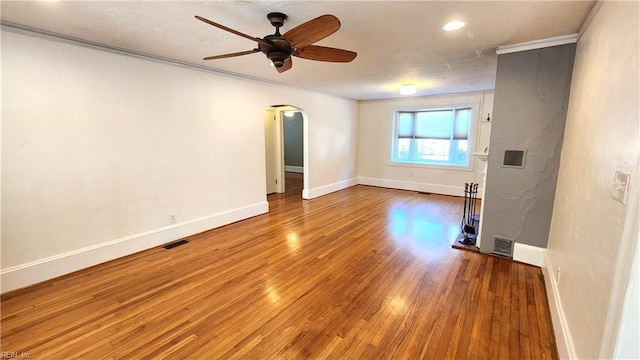unfurnished room featuring arched walkways, visible vents, crown molding, and wood finished floors