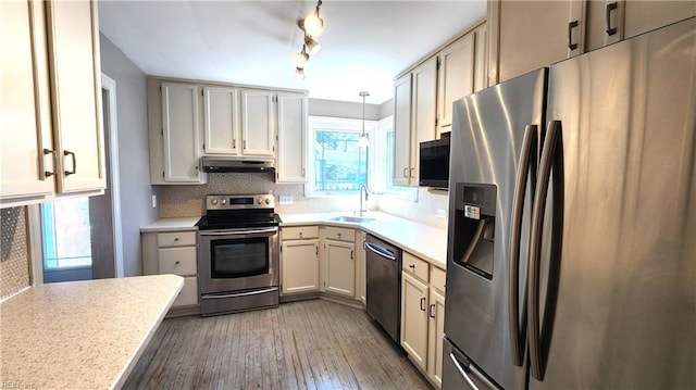 kitchen with light countertops, a sink, stainless steel appliances, and backsplash