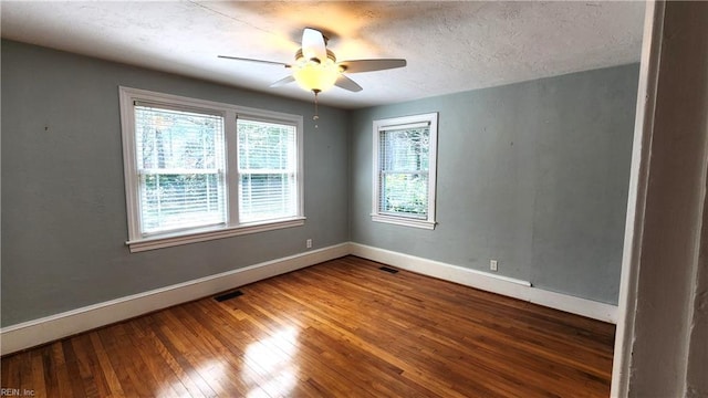 empty room with baseboards, ceiling fan, visible vents, and hardwood / wood-style flooring