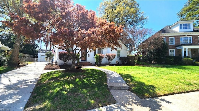 view of front of house with a gate, concrete driveway, fence, and a front lawn