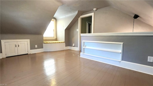 bonus room with baseboards, vaulted ceiling, and wood-type flooring