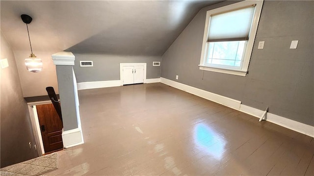 additional living space featuring baseboards, lofted ceiling, visible vents, and dark wood-type flooring