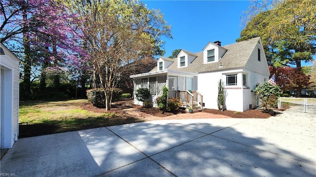 view of front of home with a sunroom, roof with shingles, and a chimney