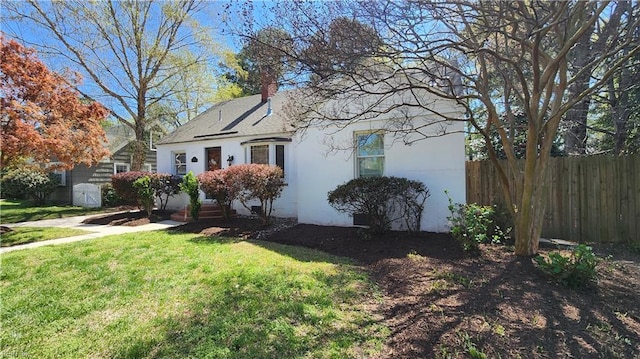 view of front of home with a front yard, stucco siding, fence, and a chimney