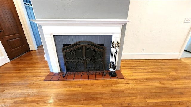 details featuring baseboards, wood finished floors, and a brick fireplace