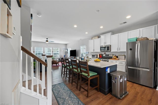 kitchen with dark wood-style floors, ceiling fan, white cabinets, visible vents, and appliances with stainless steel finishes