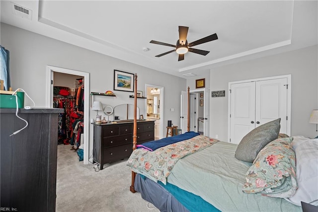 bedroom featuring light colored carpet, visible vents, a closet, and a raised ceiling
