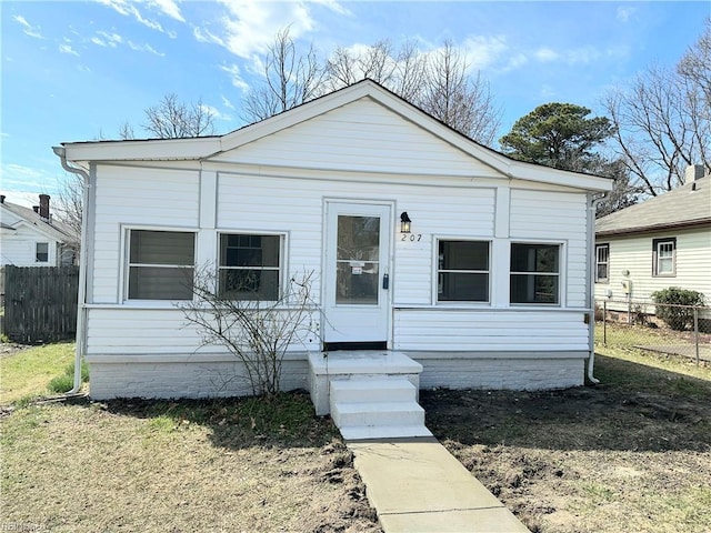 bungalow featuring a front lawn and fence
