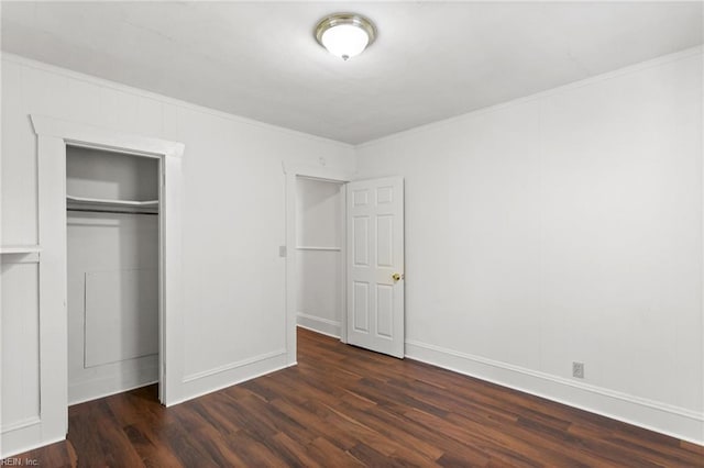 unfurnished bedroom with crown molding, baseboards, dark wood-style floors, and a closet