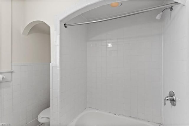 full bathroom with shower / bathtub combination, toilet, and tile walls