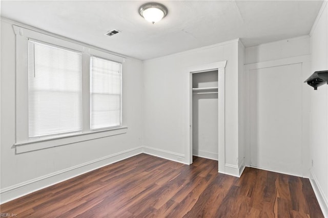 unfurnished bedroom featuring dark wood finished floors, multiple windows, visible vents, and a closet