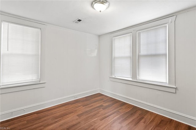 empty room with dark wood-type flooring, baseboards, and visible vents