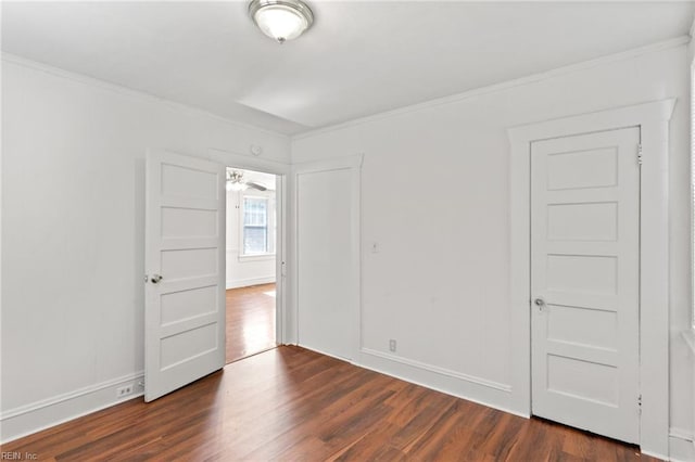 empty room featuring baseboards, ornamental molding, and dark wood-style floors
