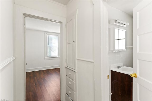 corridor with baseboards, dark wood-style floors, and a sink