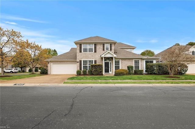 traditional-style home featuring a front lawn, driveway, and an attached garage