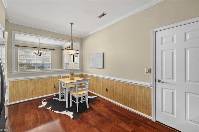 dining area featuring a wainscoted wall, visible vents, a chandelier, ornamental molding, and wood finished floors