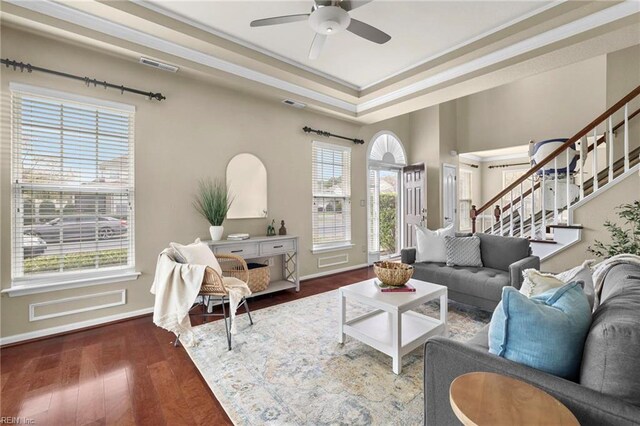 living room featuring ceiling fan, visible vents, stairs, and wood finished floors