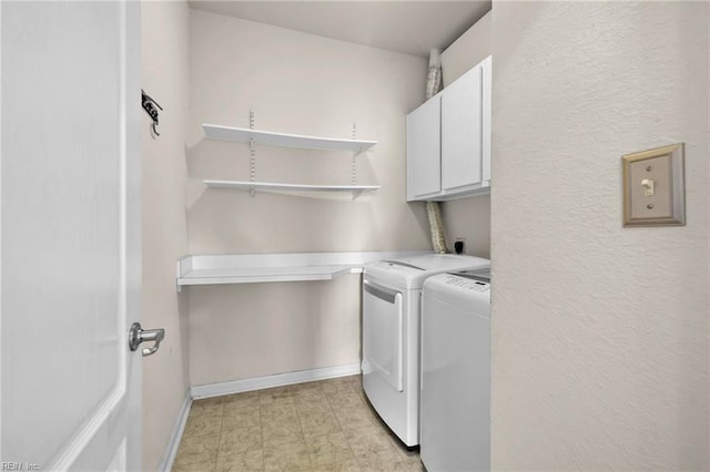laundry area featuring washing machine and clothes dryer, cabinet space, and baseboards