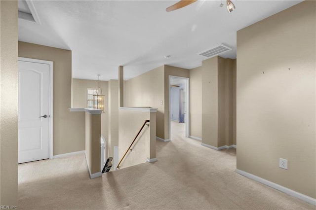 corridor with baseboards, visible vents, an upstairs landing, and carpet floors