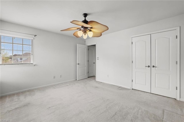 unfurnished bedroom with a closet, carpet flooring, baseboards, and a ceiling fan