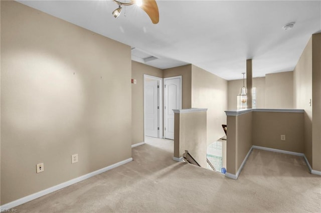 carpeted spare room featuring baseboards and ceiling fan