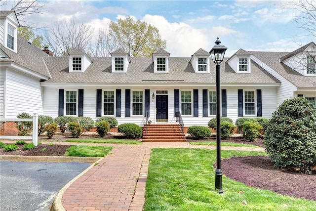 cape cod-style house with a shingled roof and a front yard