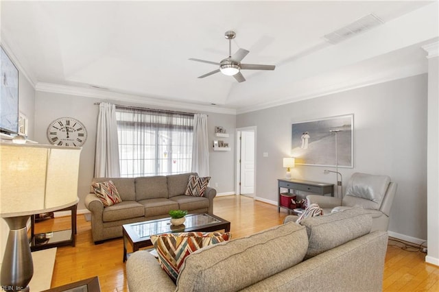 living area with a tray ceiling, light wood-type flooring, baseboards, visible vents, and ceiling fan