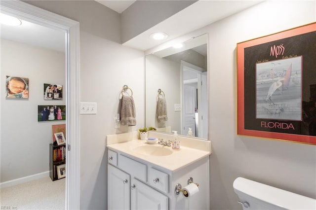bathroom with baseboards, toilet, and vanity