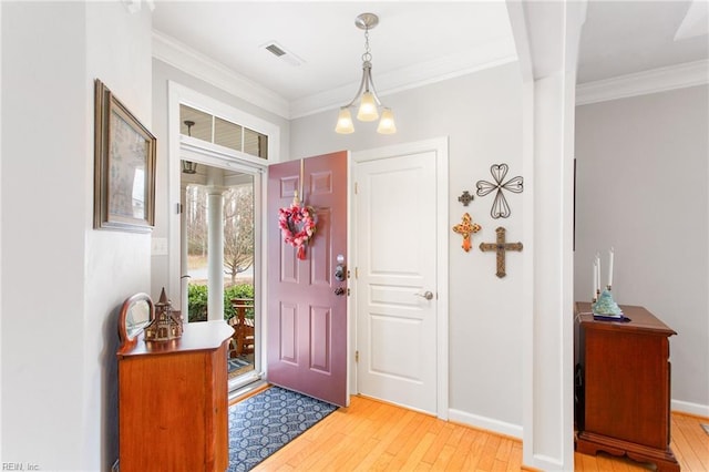 foyer entrance with ornamental molding, baseboards, light wood finished floors, and visible vents