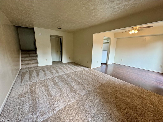 empty room with baseboards, a textured ceiling, visible vents, ceiling fan, and wood finished floors