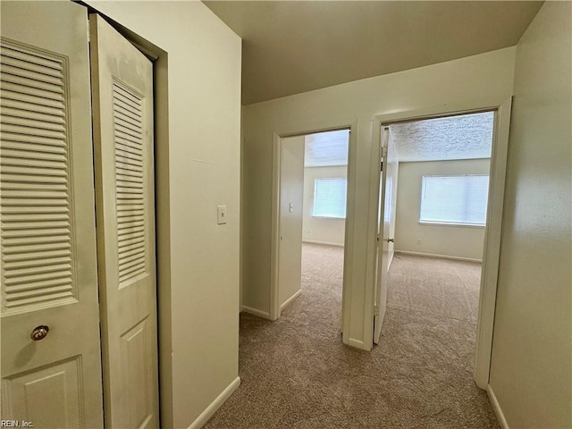 corridor featuring baseboards and carpet floors