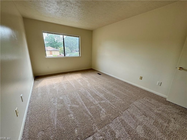 carpeted empty room with baseboards and a textured ceiling