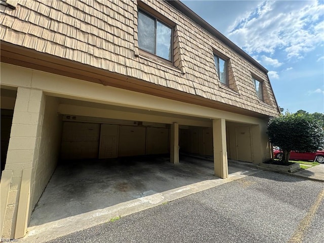 view of side of home featuring concrete block siding, mansard roof, and an attached garage