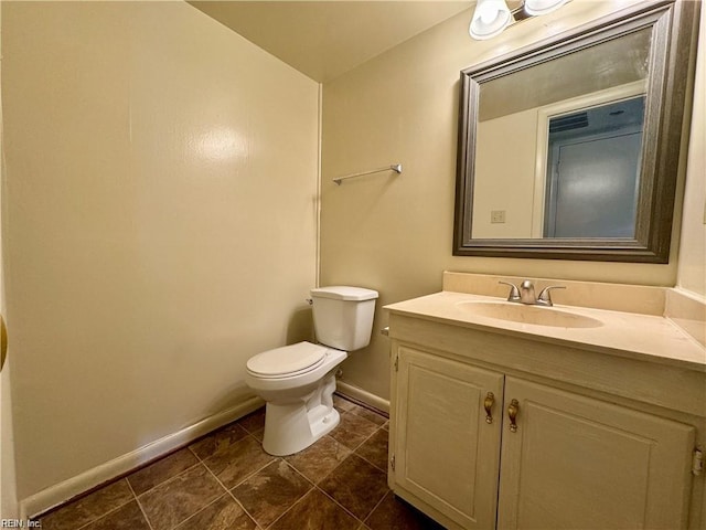 bathroom with toilet, vanity, and baseboards