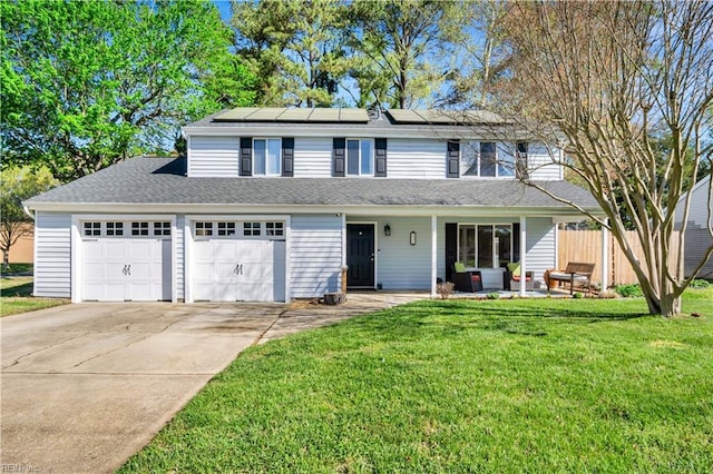 traditional-style home featuring a front lawn, an attached garage, solar panels, and concrete driveway