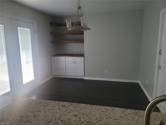 unfurnished dining area with baseboards, dark wood-style floors, and a healthy amount of sunlight