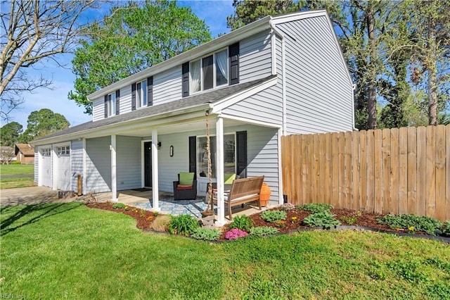 traditional home with a front yard, an attached garage, fence, and concrete driveway