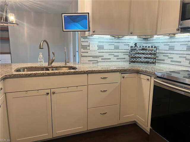 kitchen featuring appliances with stainless steel finishes, a sink, backsplash, and white cabinets