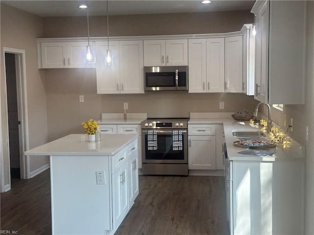 kitchen featuring white cabinets, a sink, dark wood-style flooring, a kitchen island, and appliances with stainless steel finishes