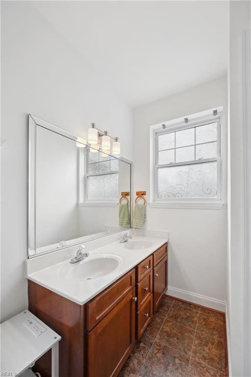bathroom featuring double vanity, a sink, and baseboards