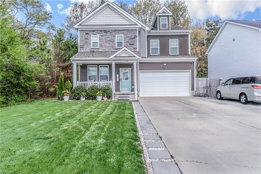 view of front of house featuring an attached garage, stone siding, driveway, a front lawn, and a porch
