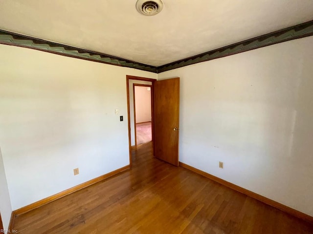 empty room featuring visible vents, baseboards, and wood finished floors