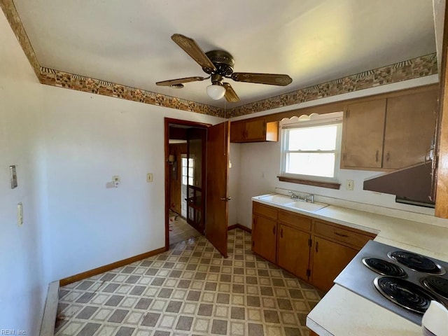 kitchen with baseboards, light countertops, light floors, a sink, and ceiling fan