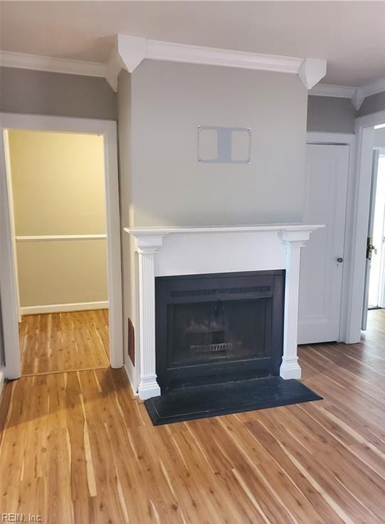 interior details featuring a fireplace with flush hearth, wood finished floors, and ornamental molding