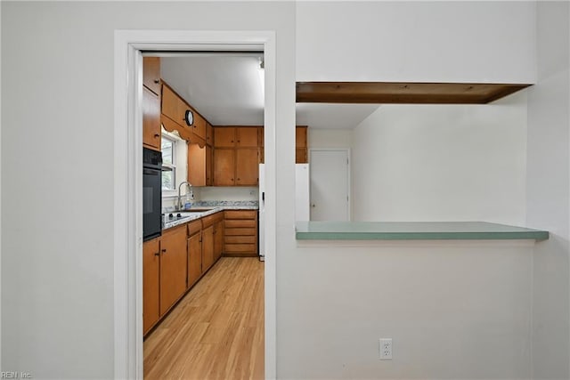 8084 Lynnbrook Dr, Norfolk, VA 23518 - kitchen featuring light wood-style flooring, brown cabinetry, light countertops, a sink, and black appliances